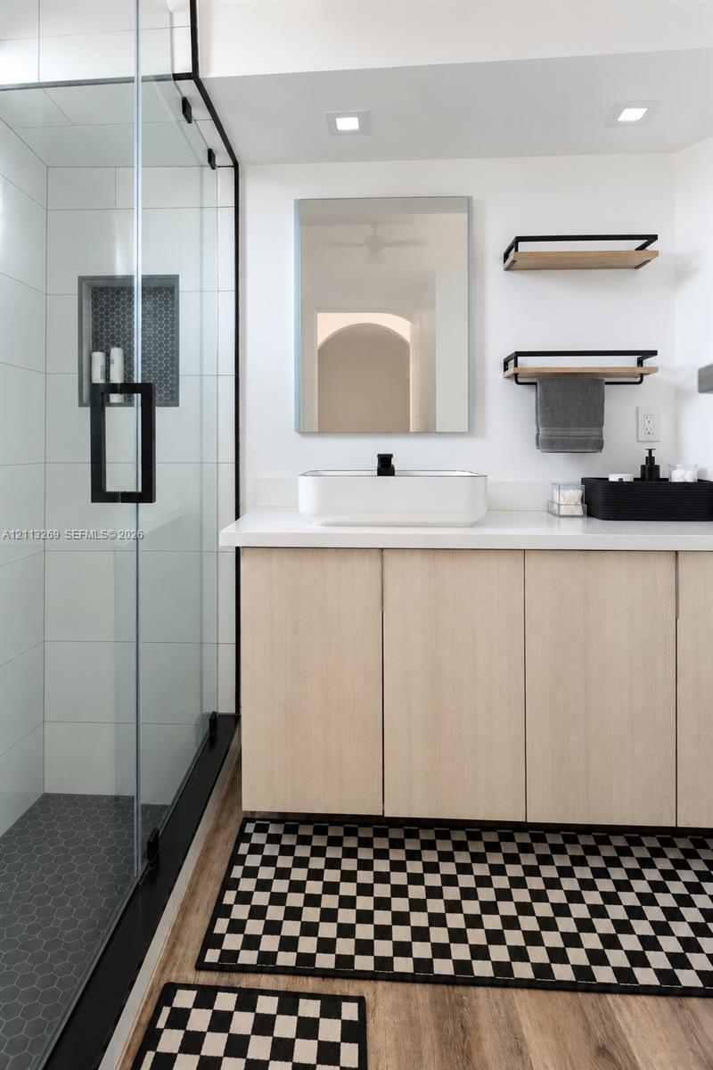 Vanity featuring light wood-finish cabinetry, a rectangular vessel sink, and a solid-surface countertop
