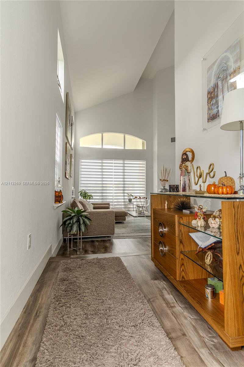 Vaulted ceilings, wood-finish flooring, and an arched transom window