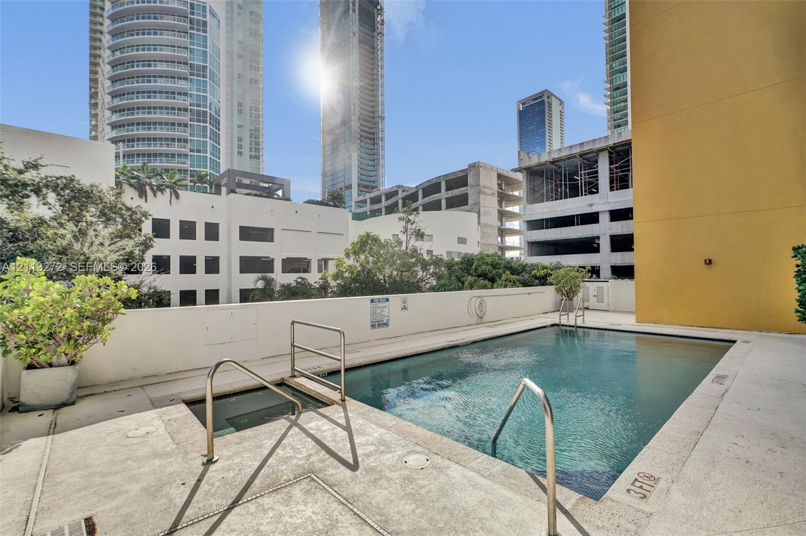 Swimming pool featuring a concrete deck, built-in metal handrails, and a dedicated wading area
