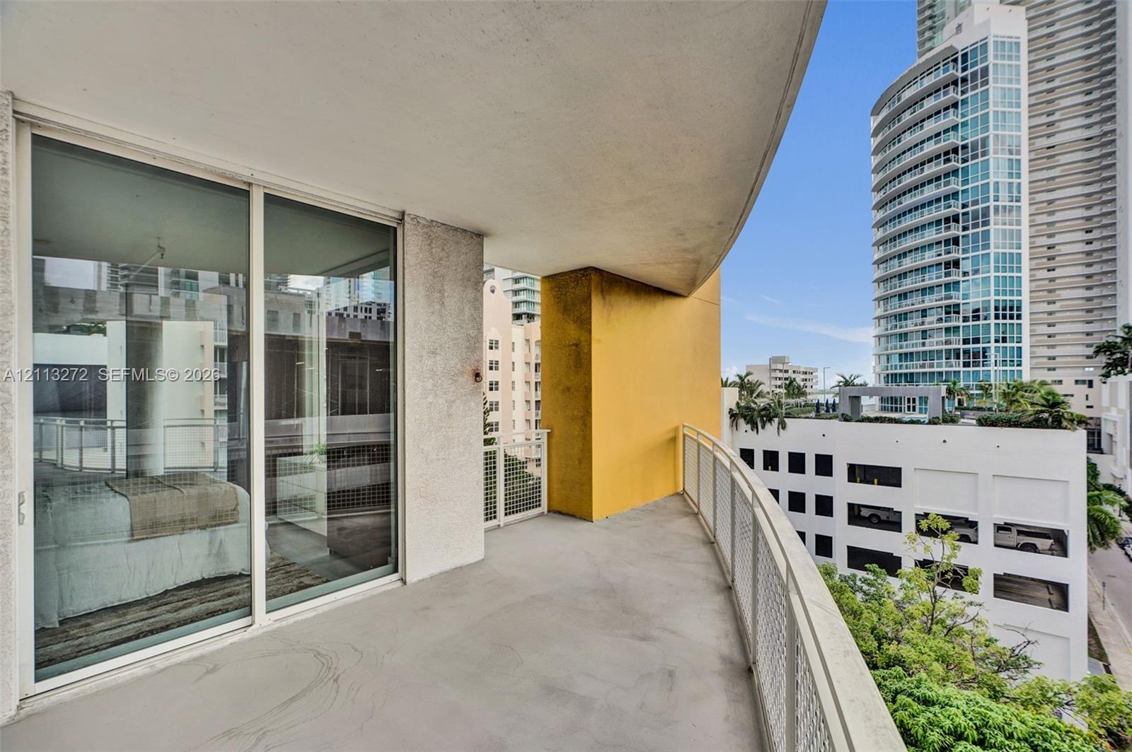 Curved balcony featuring concrete flooring, a metal mesh railing, and sliding glass entry doors