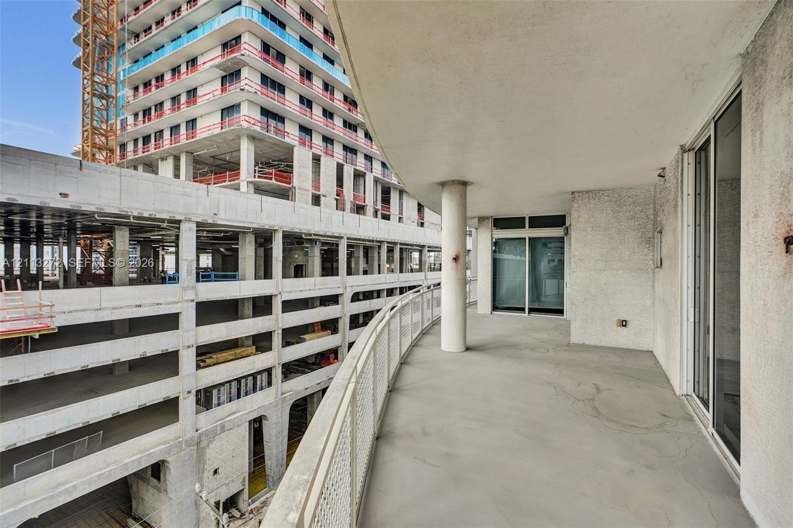 Curved covered balcony featuring concrete flooring, a structural column, and a metal grid railing