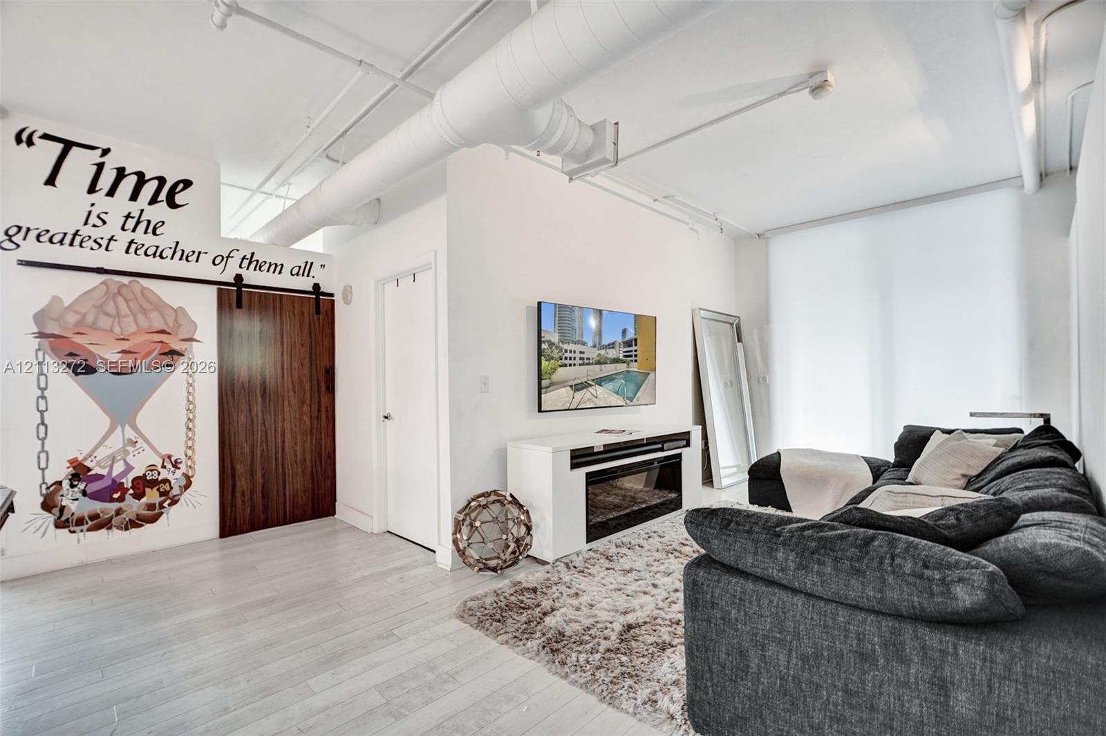 Industrial-style interior featuring high ceilings with exposed ductwork, wood-finish flooring, and a sliding barn-style door
