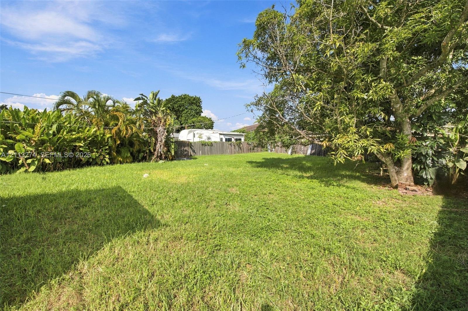Expansive backyard featuring a lawn, perimeter wood fencing, and mature trees Expansive backyard featuring a lawn, perimeter wood fencing, and mature trees