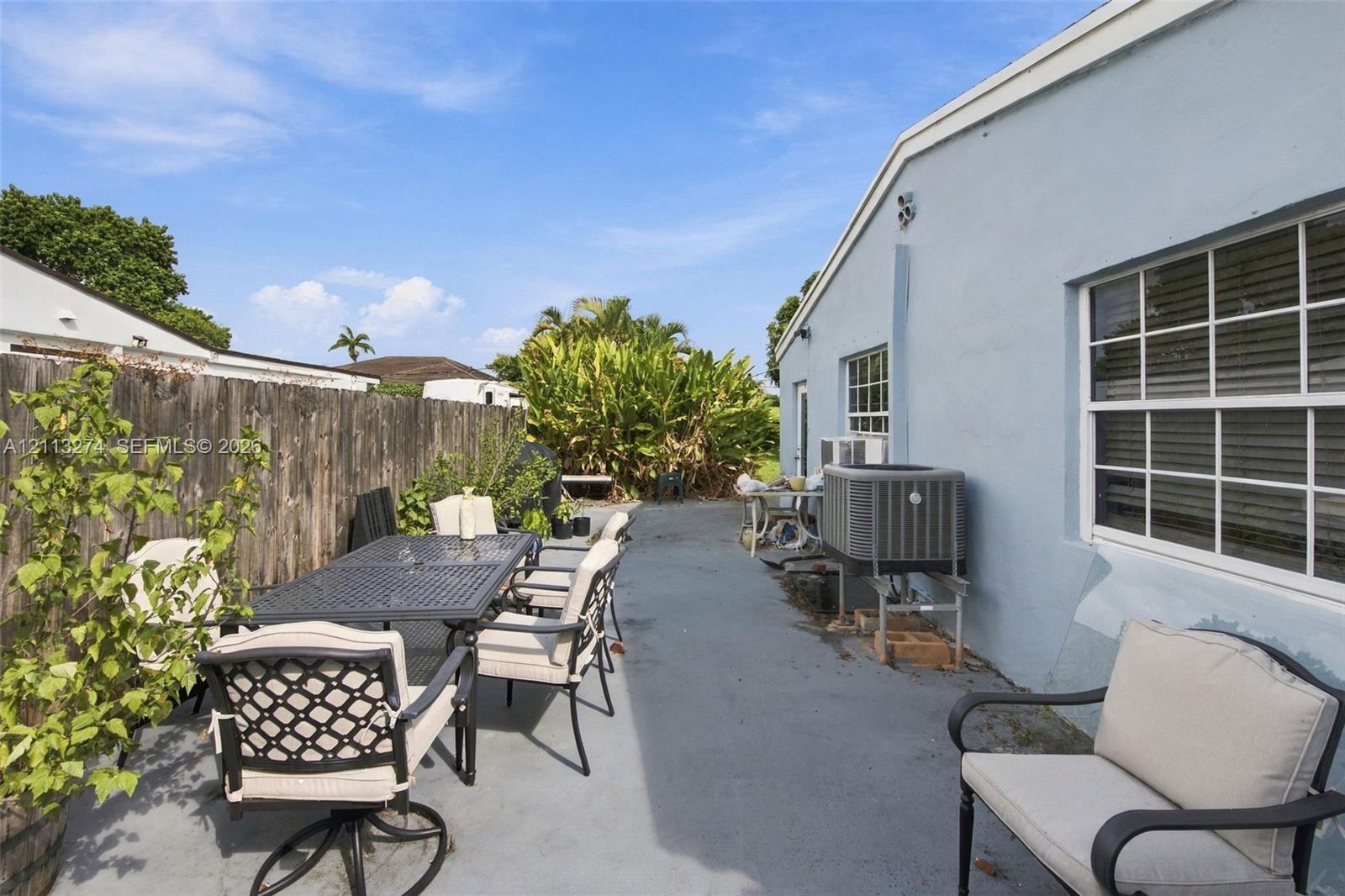 Concrete patio area featuring a wood-panel fence and exterior siding