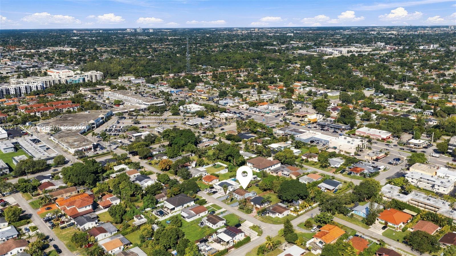 Aerial perspective of a residential lot featuring mature trees, landscaped greenery, and a suburban setting