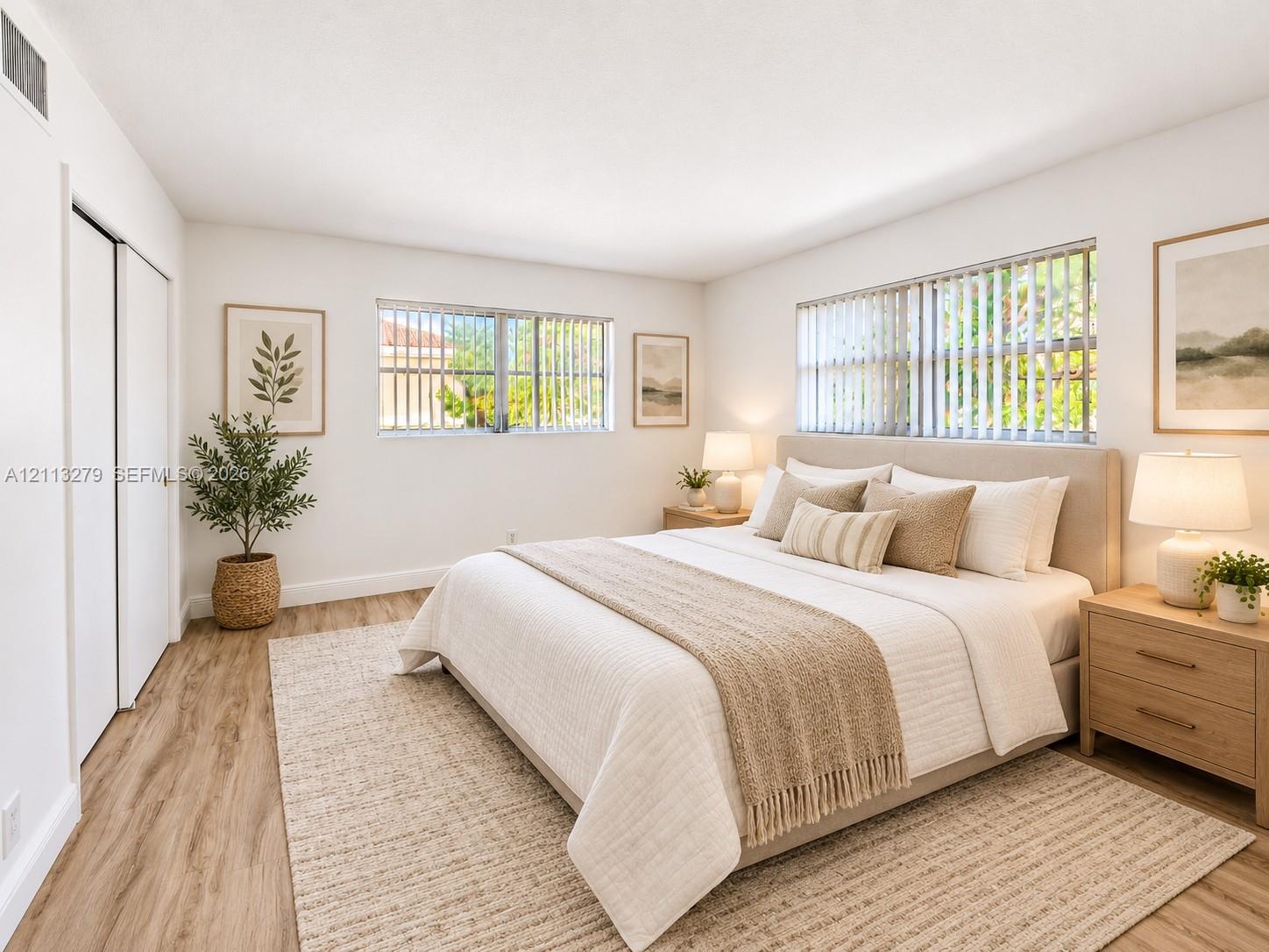 Bedroom featuring wood-finish flooring, dual-aspect windows with vertical blinds, and a built-in double-door closet