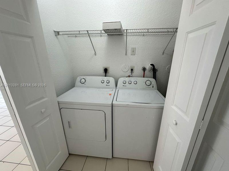 Laundry closet featuring dual bifold doors, tile flooring, and integrated wire shelving