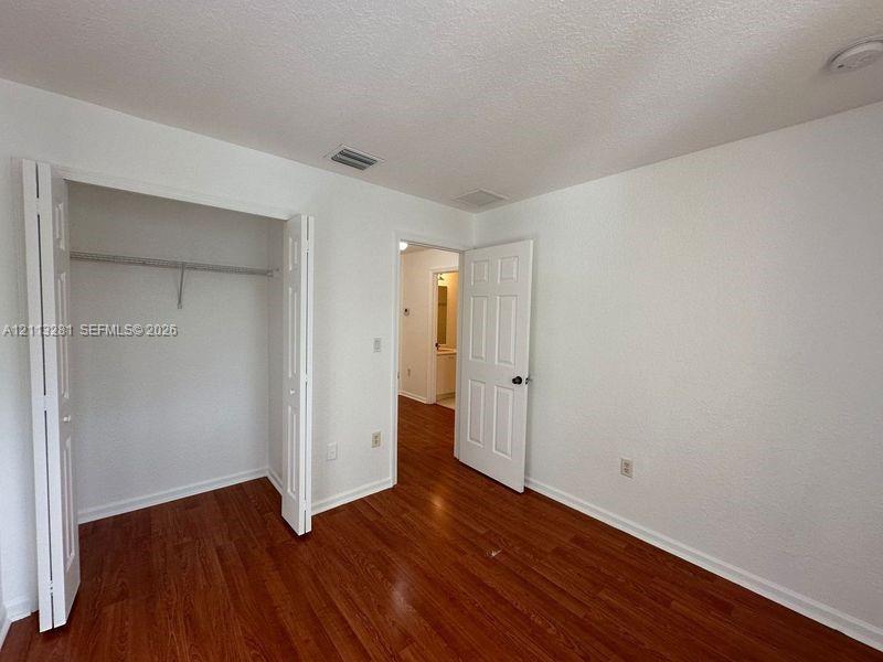 Room featuring wood-finish flooring, a bi-fold door closet with built-in shelving, and a six-panel interior door