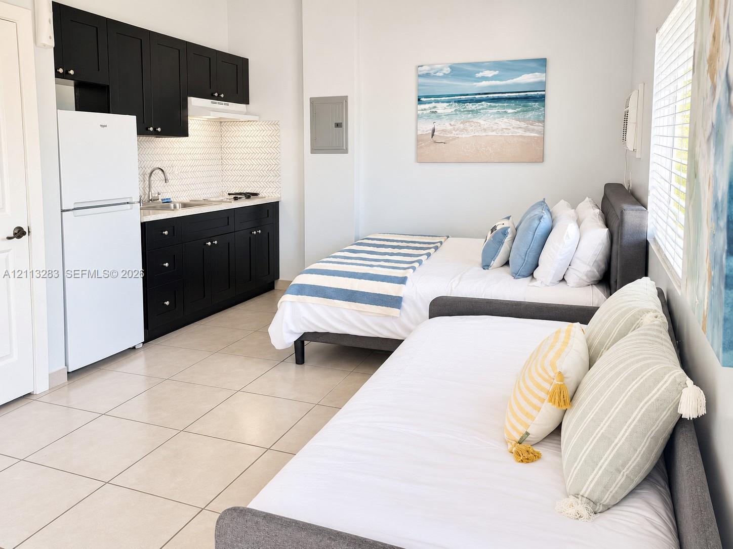 Kitchenette featuring black cabinetry, white countertops, a hexagonal tile backsplash, and ceramic floor tiling