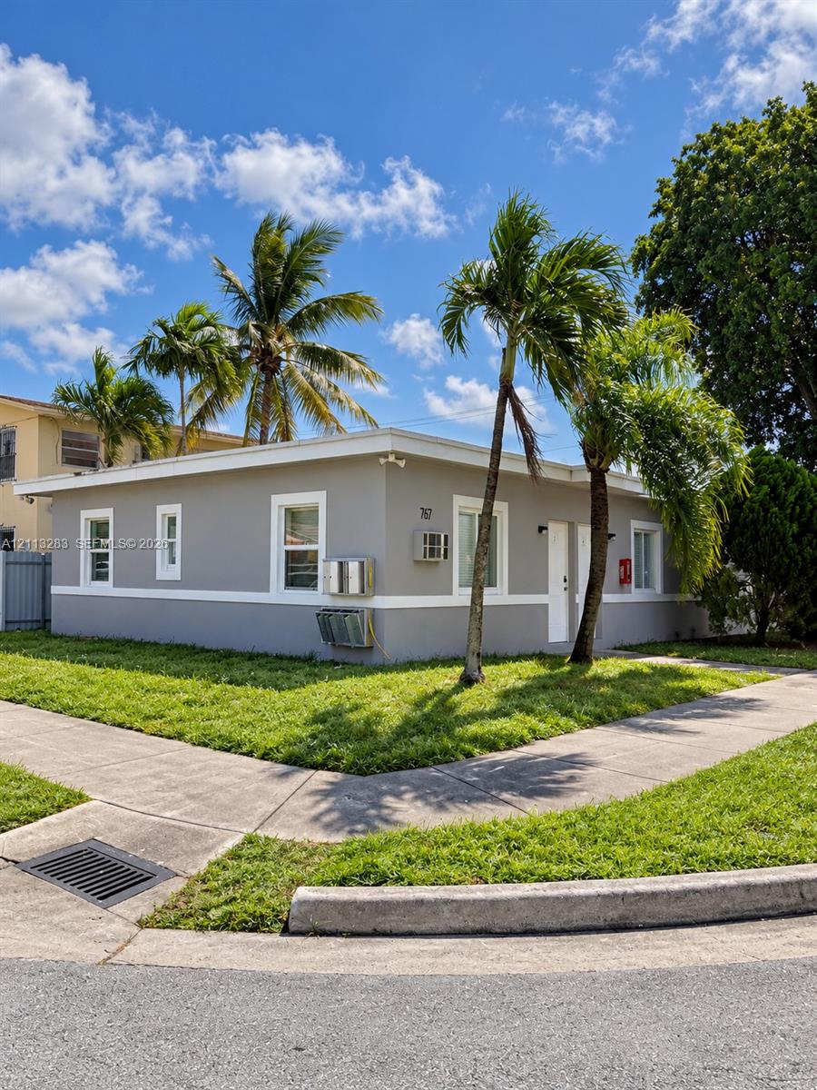Single-story exterior featuring a neutral painted finish, crisp white trim, and established palm trees situated on a corner lot Single-story exterior featuring a neutral painted finish, crisp white trim, and established palm trees situated on a corner lot