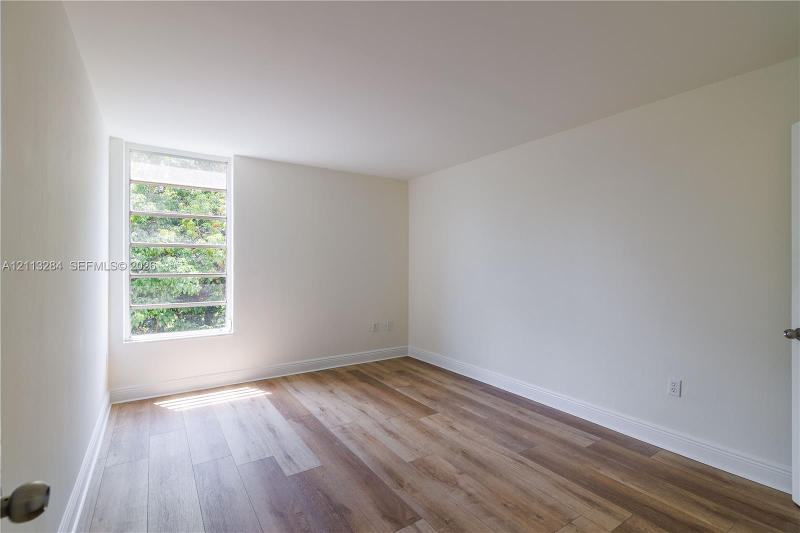 Neutral interior room featuring wood-finish flooring and a multi-pane horizontal window
