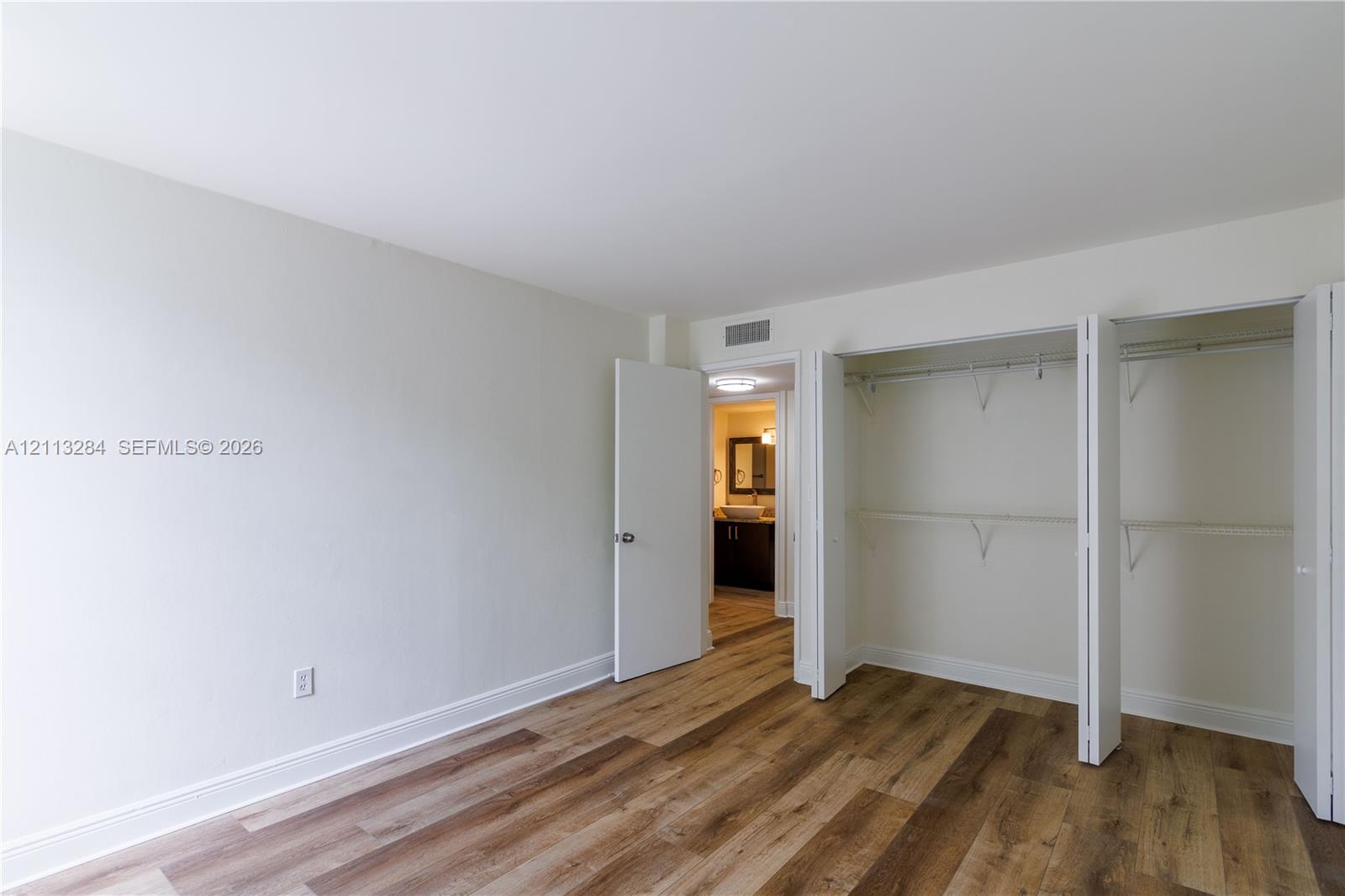 Wood-finish flooring, neutral wall tones, and a dual-panel closet with built-in shelving
