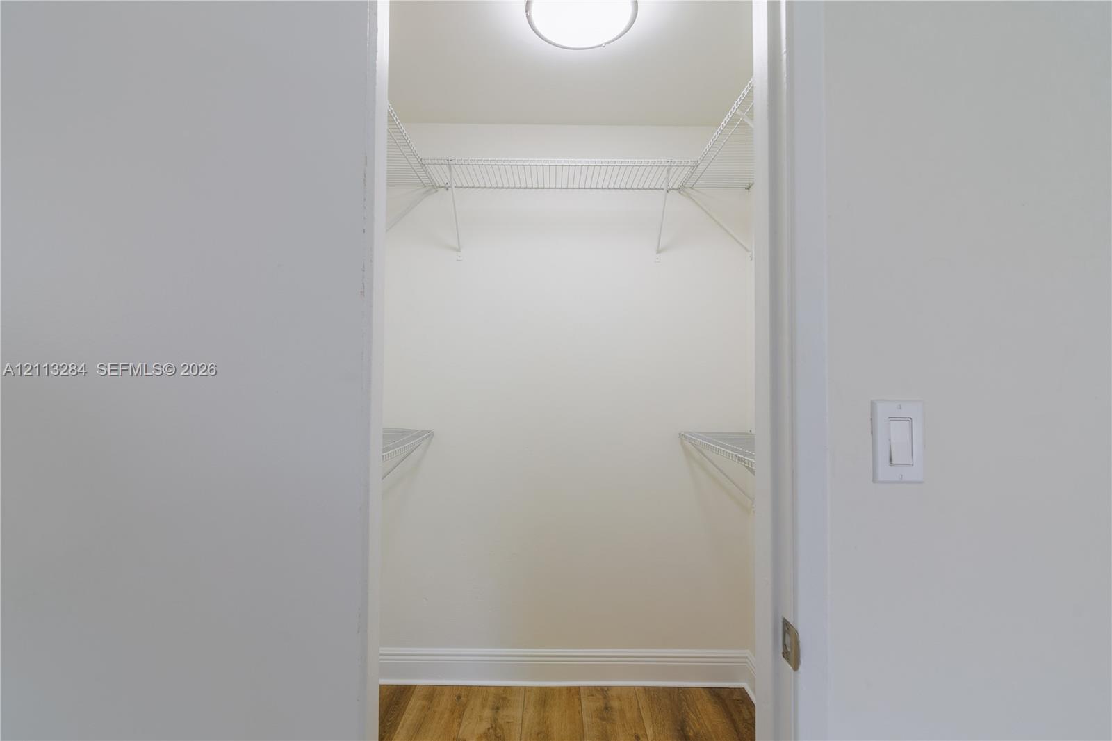 Walk-in closet featuring wood-finish flooring, white walls, and integrated wire shelving