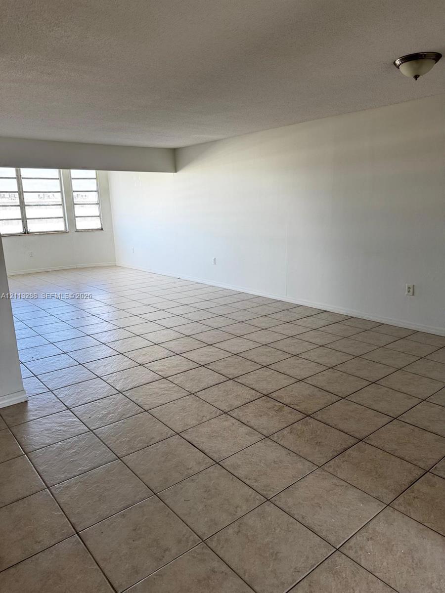 Expansive room featuring large multi-pane windows and neutral ceramic tile flooring Expansive room featuring large multi-pane windows and neutral ceramic tile flooring