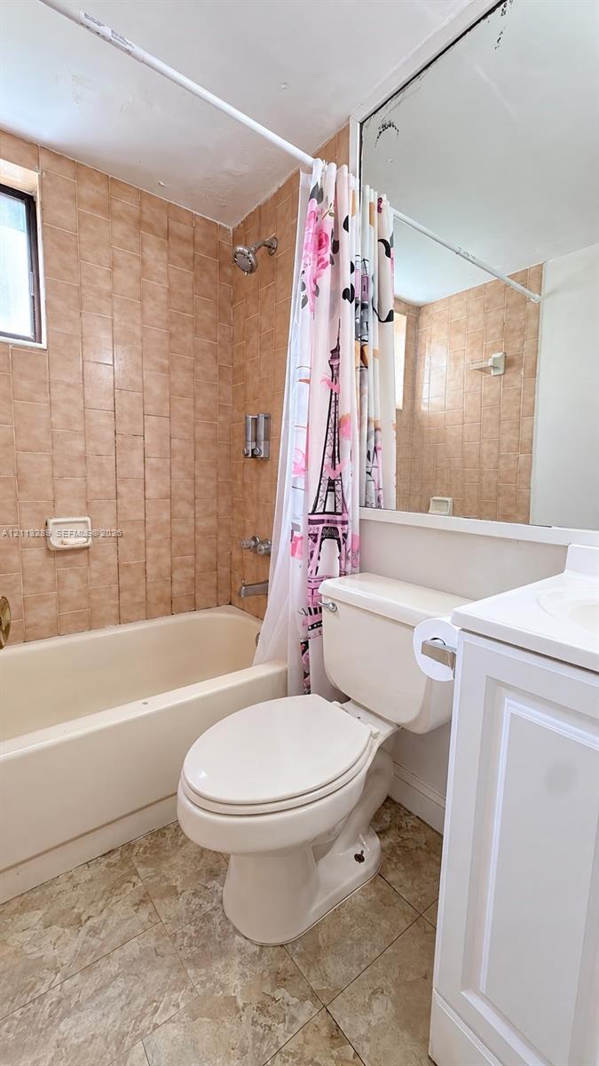 Full-height wall tiling, integrated bathtub, large wall-mounted mirror, white vanity cabinetry, and tile flooring