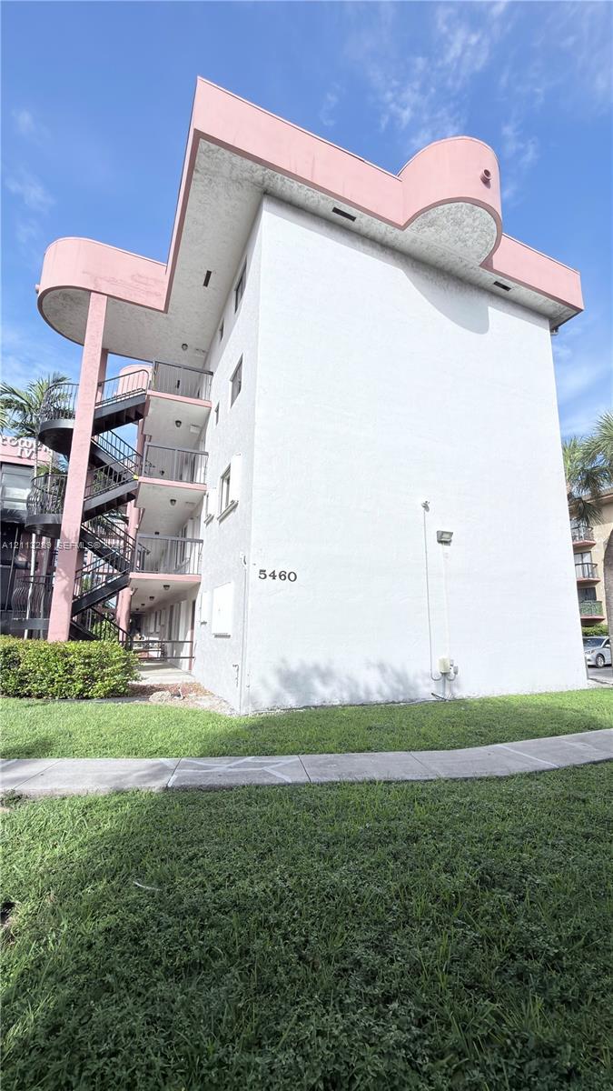 Mid-rise building featuring a stucco exterior, curvilinear architectural accents, multi-level exterior staircases, and concrete walkways