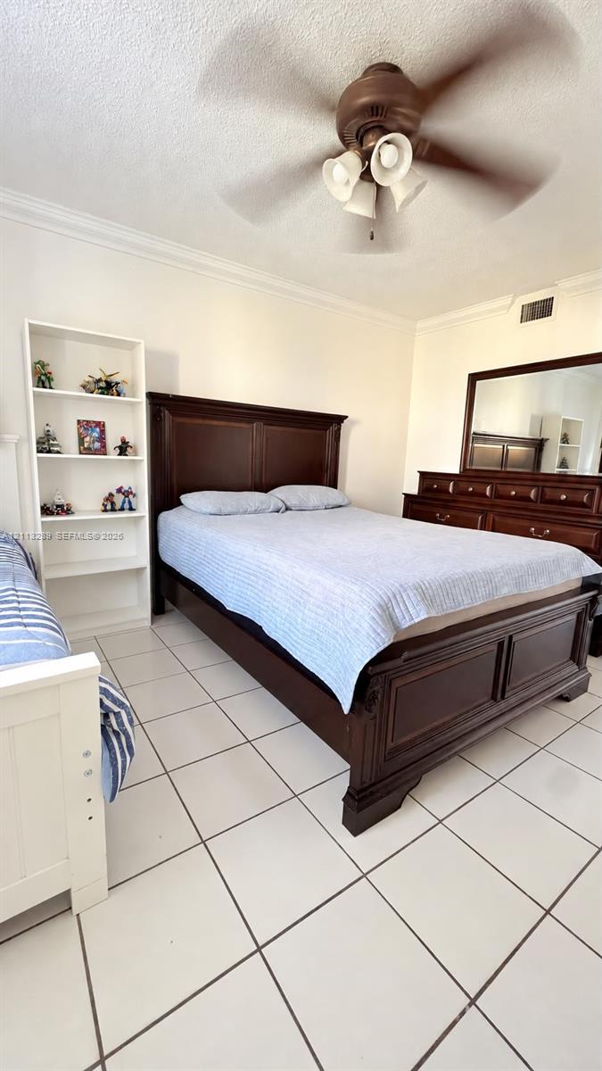 White tile flooring, built-in shelving unit, and a ceiling fan with integrated light fixture