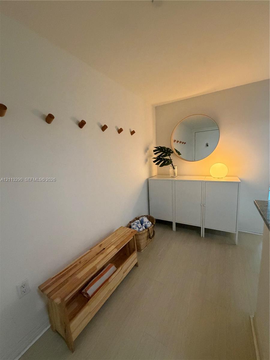 Wall-mounted wood peg hooks, circular wall mirror, and wood-finish flooring Wall-mounted wood peg hooks, circular wall mirror, and wood-finish flooring