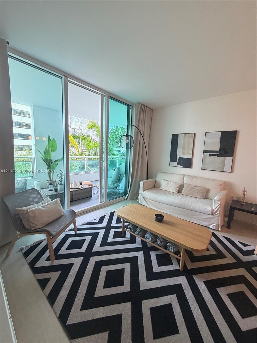 Floor-to-ceiling glass sliding doors, private balcony with metal railing, and neutral wall finishes Floor-to-ceiling glass sliding doors, private balcony with metal railing, and neutral wall finishes