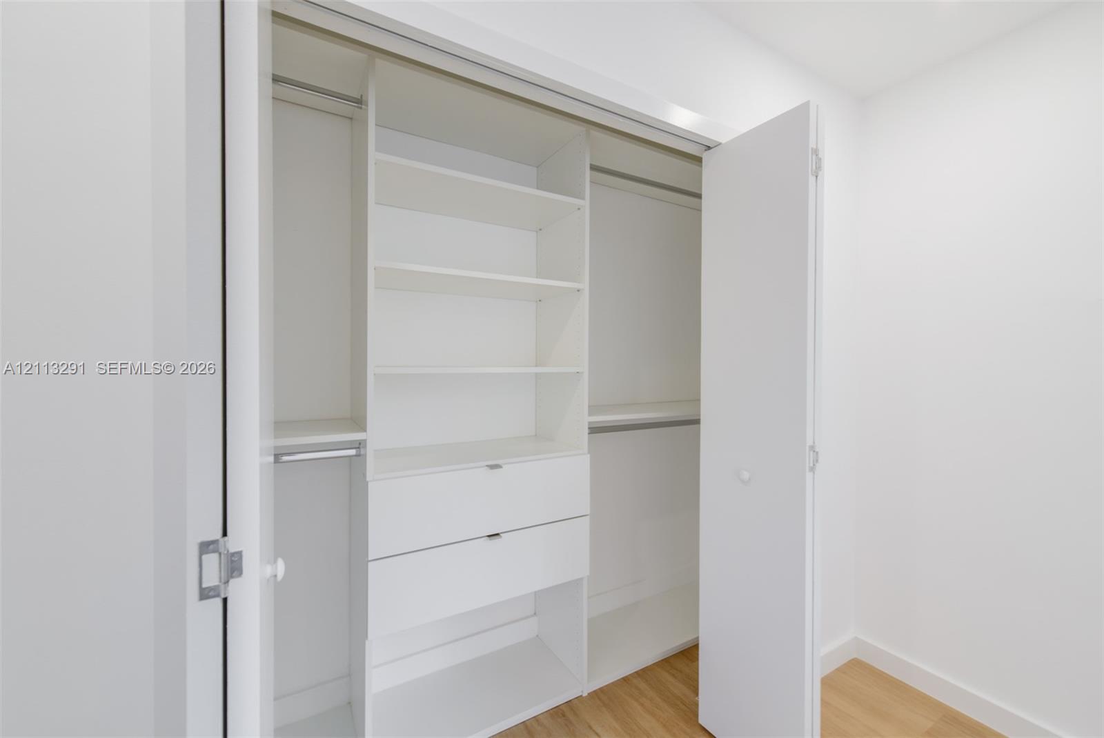 Built-in closet organizer featuring white shelving, integrated drawers, and dual hanging rods