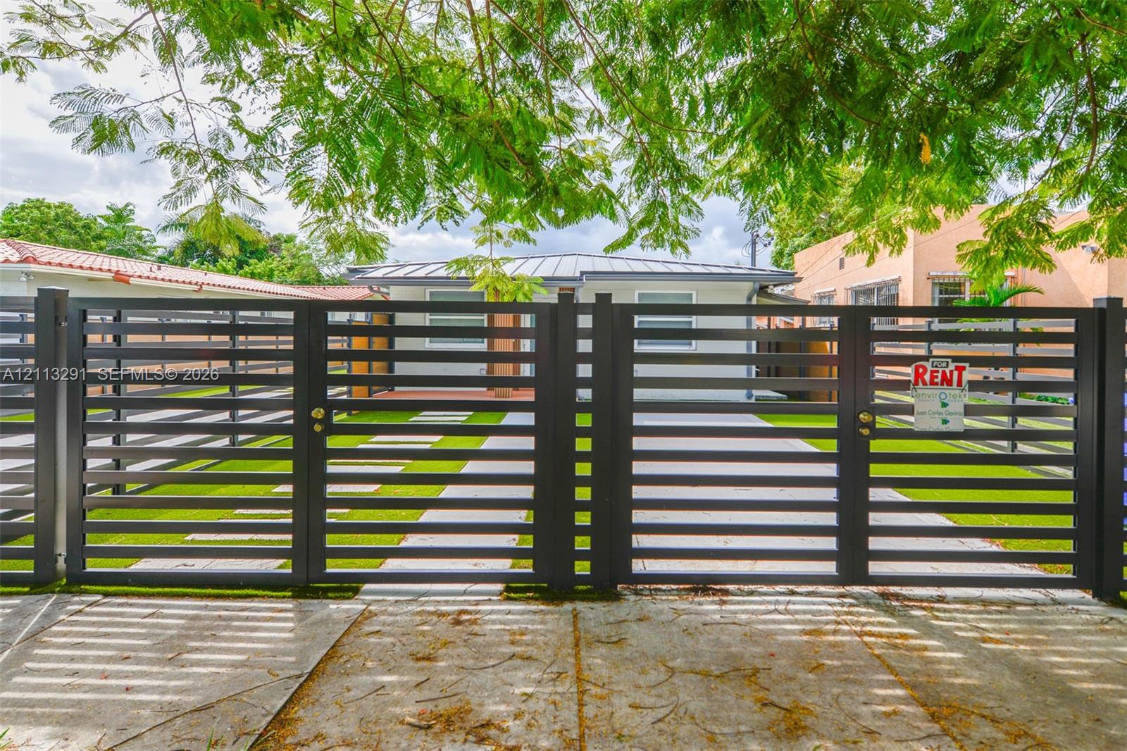Horizontal slat metal entry gate with concrete paver walkway and synthetic turf lawn Horizontal slat metal entry gate with concrete paver walkway and synthetic turf lawn