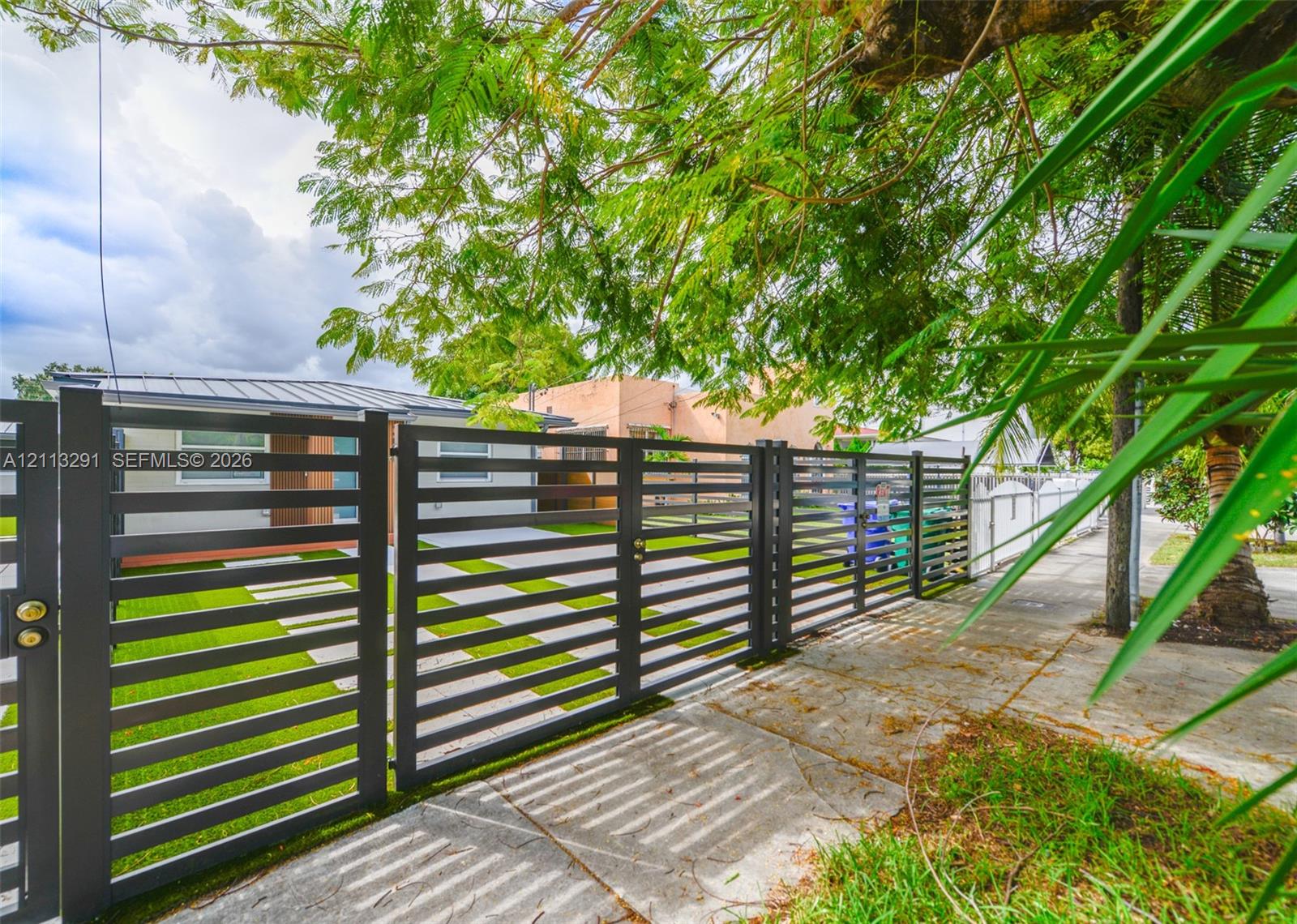 Horizontal slat metal fencing with integrated gate, artificial turf yard, and concrete paver driveway Horizontal slat metal fencing with integrated gate, artificial turf yard, and concrete paver driveway