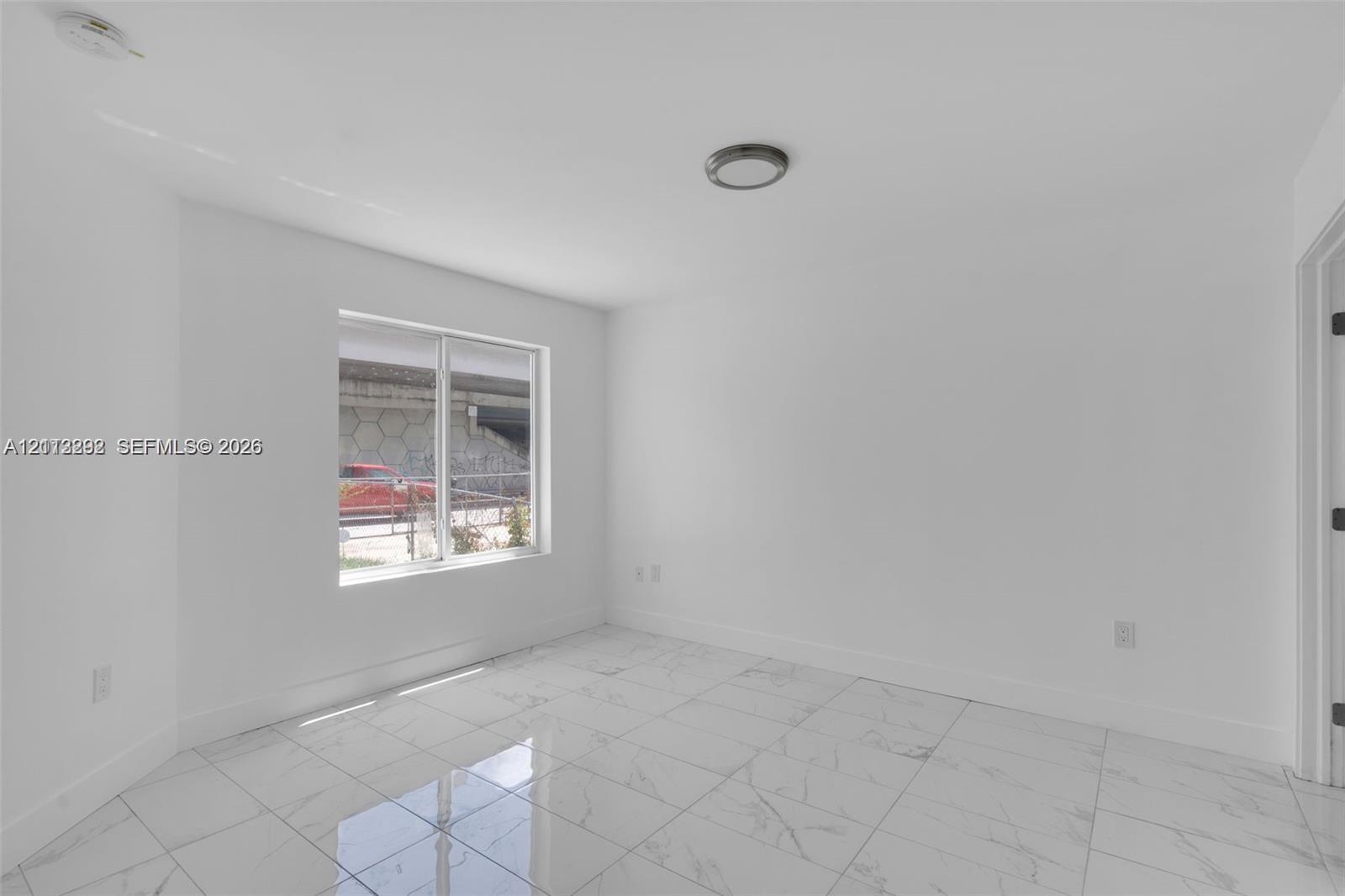 Interior space featuring white walls, large-format tile flooring with a marble-finish pattern, and a flush-mount ceiling light fixture