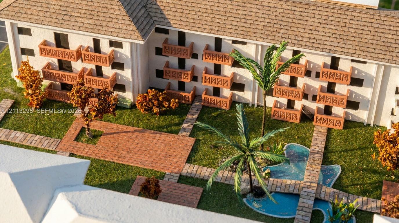 Multi-level structure featuring a neutral exterior, decorative balustraded balconies, shingled roof, brick-paved walkways, and a manicured landscape with a water feature