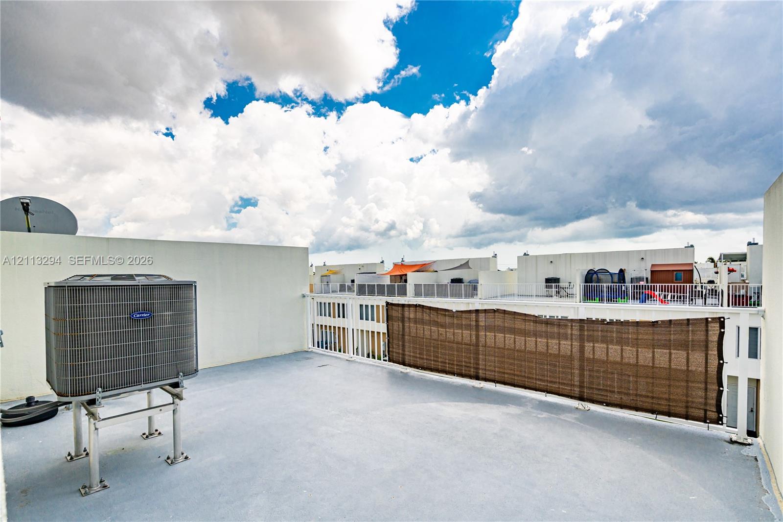 Rooftop deck with solid wall perimeter, white metal railing, and high-capacity exterior HVAC unit