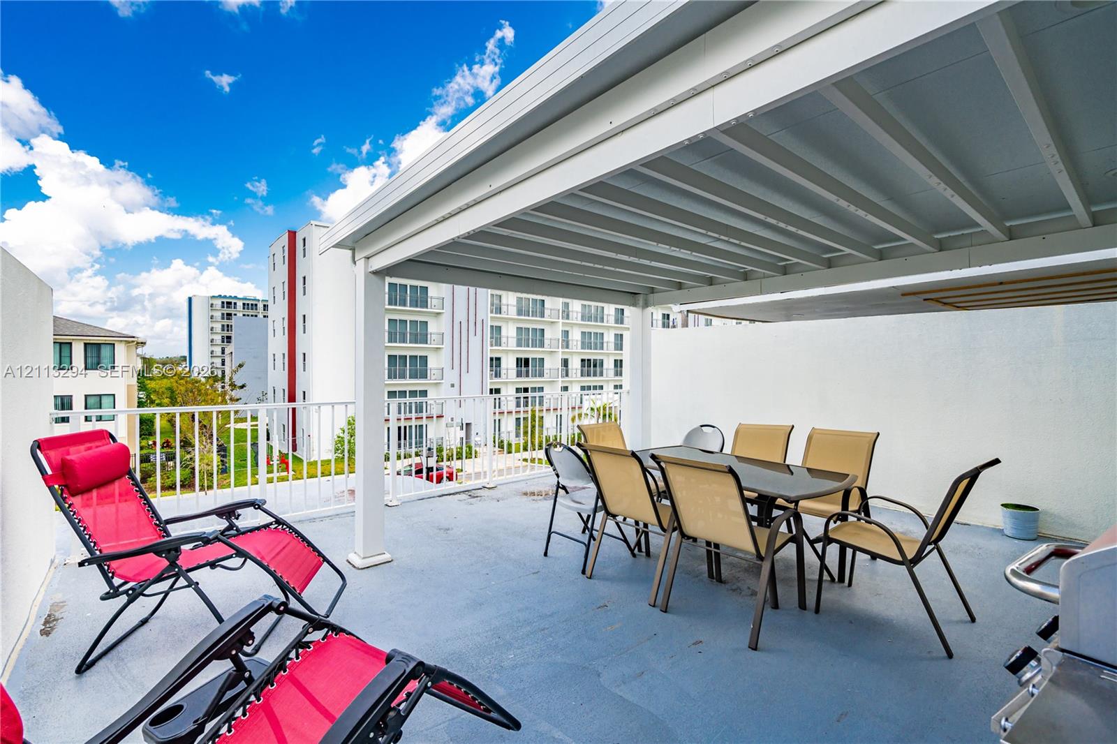 Covered terrace featuring a flat-surface deck, white metal railings, and an integrated overhead canopy