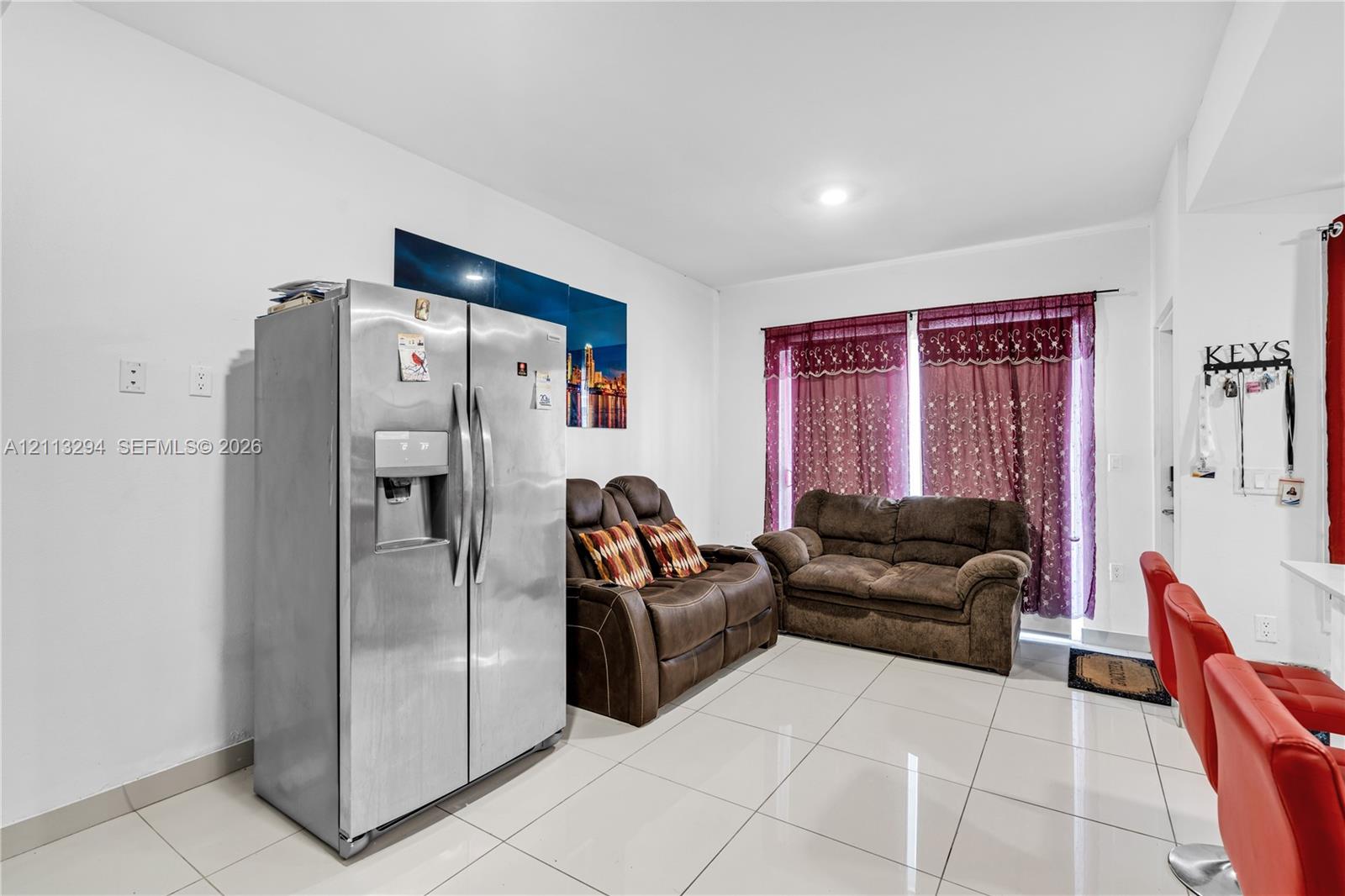 Polished ceramic tile flooring throughout, stainless steel side-by-side refrigerator, and recessed ceiling lighting