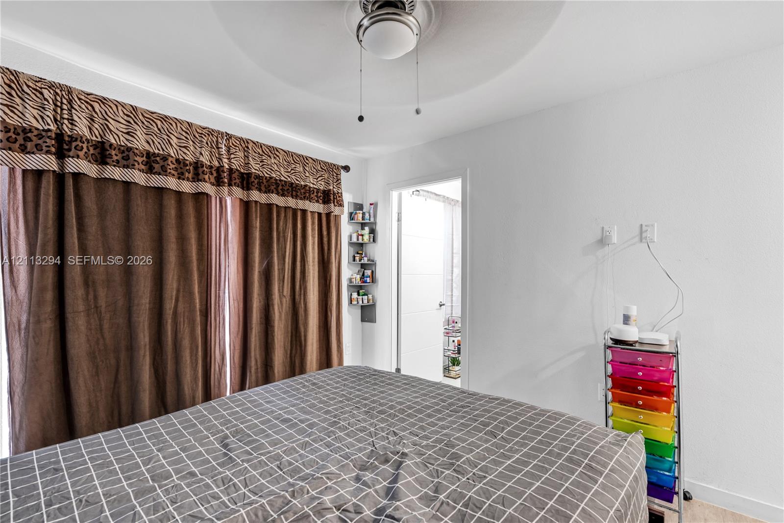 Ceiling-mounted light fixture with integrated fan, wall-mounted corner shelving unit, and recessed doorway