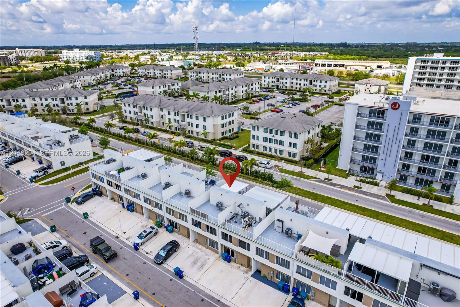 Aerial perspective of a multi-level residential structure featuring white exterior facades, flat rooflines, and rooftop terraces with metal railing enclosures Aerial perspective of a multi-level residential structure featuring white exterior facades, flat rooflines, and rooftop terraces with metal railing enclosures