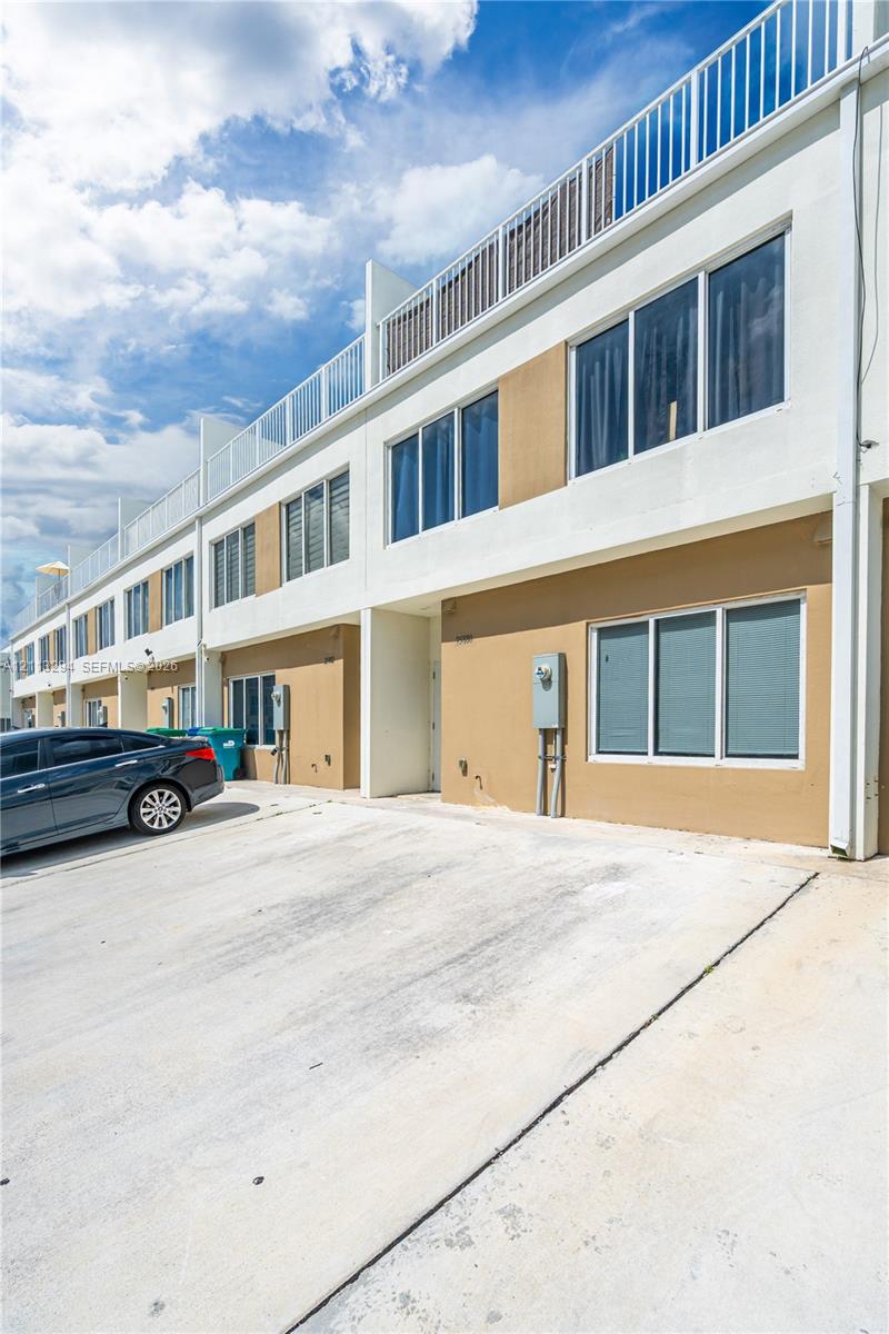 Contemporary multi-story exterior featuring a concrete driveway, smooth stucco finish, oversized windows, and a railed rooftop terrace Contemporary multi-story exterior featuring a concrete driveway, smooth stucco finish, oversized windows, and a railed rooftop terrace