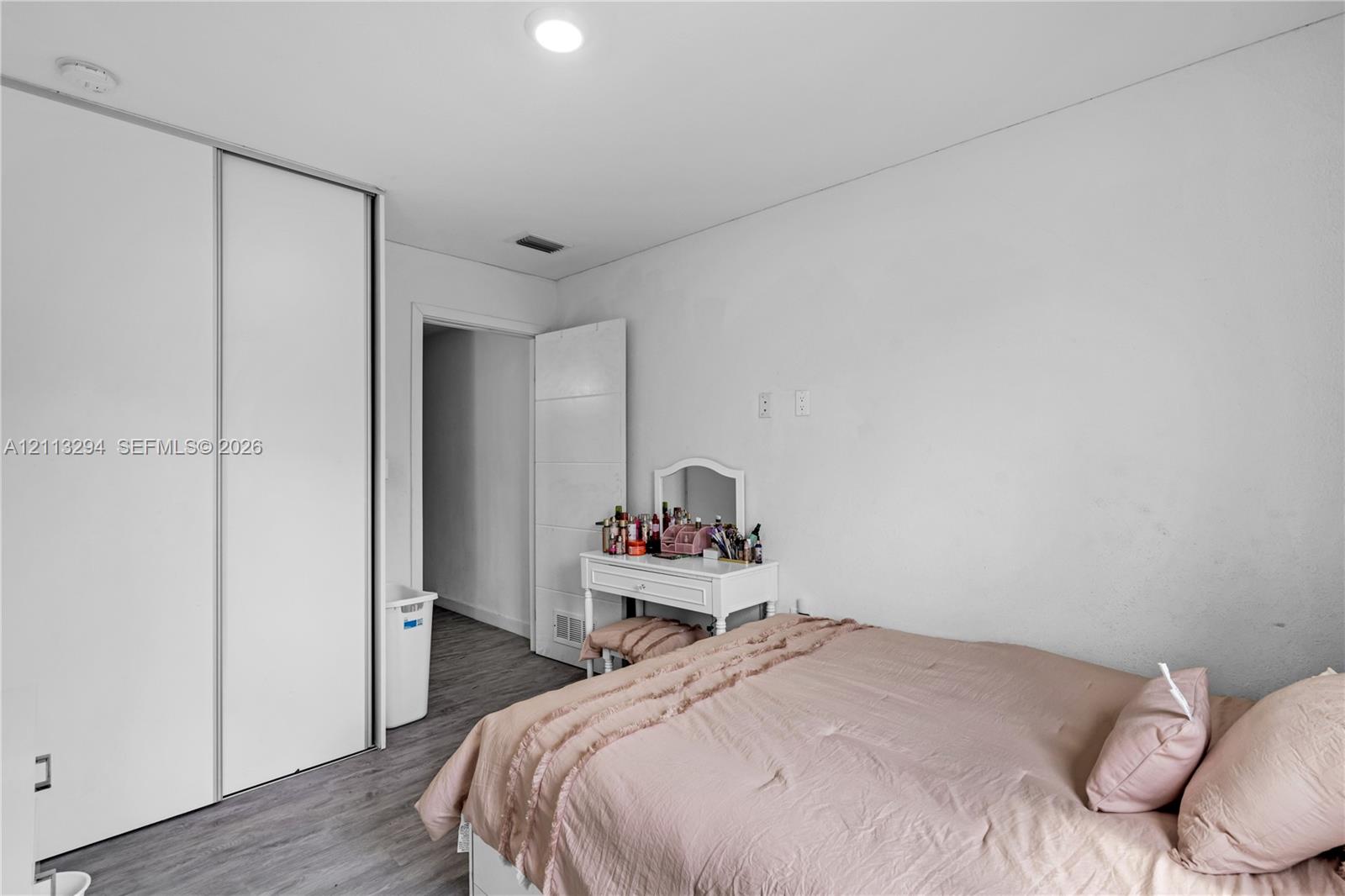 Neutral-toned room featuring wood-finish flooring, recessed lighting, and a floor-to-ceiling sliding closet door