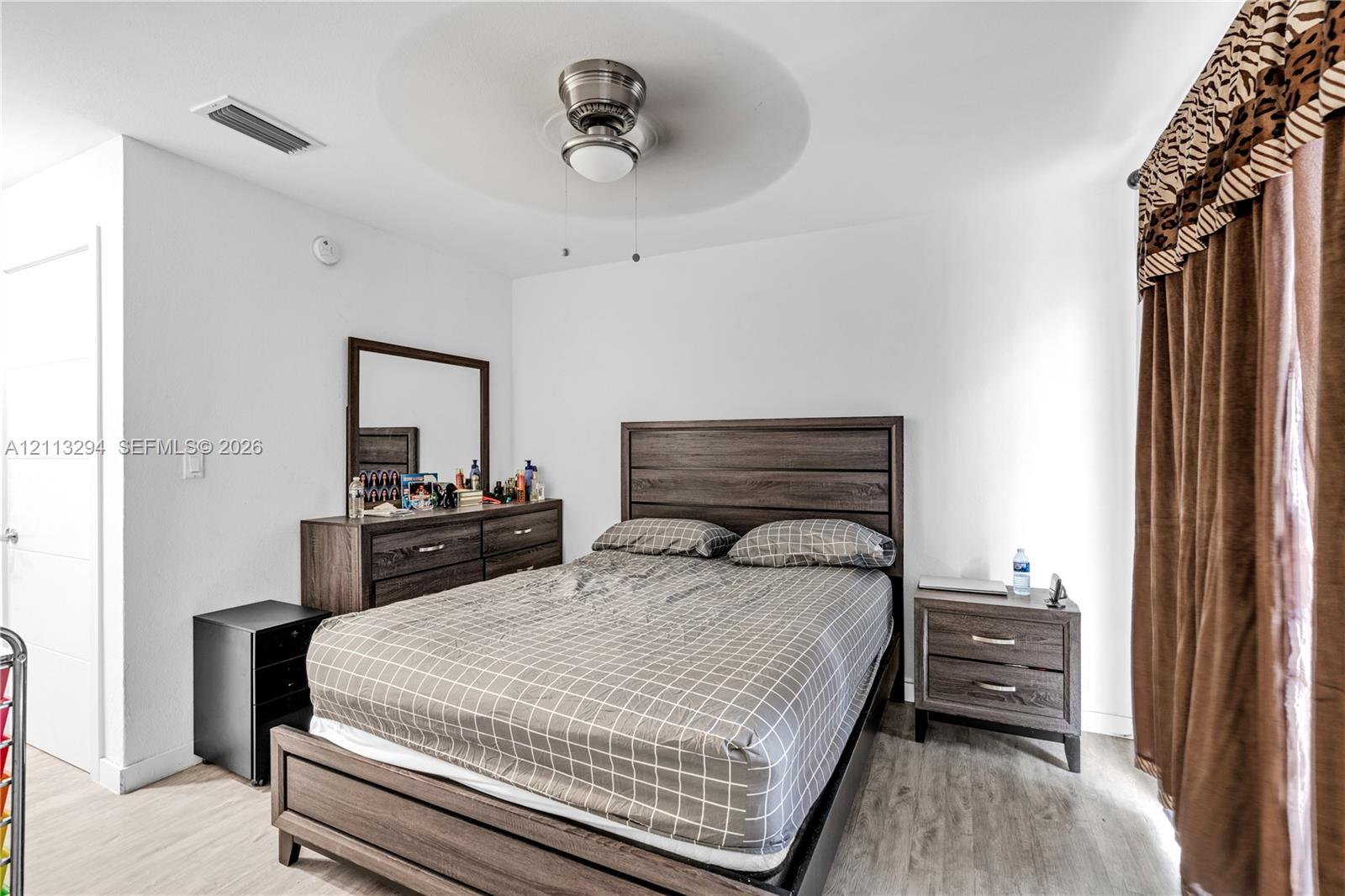 Neutral-toned wall finish, wood-finish flooring, and a ceiling-mounted fan with integrated lighting