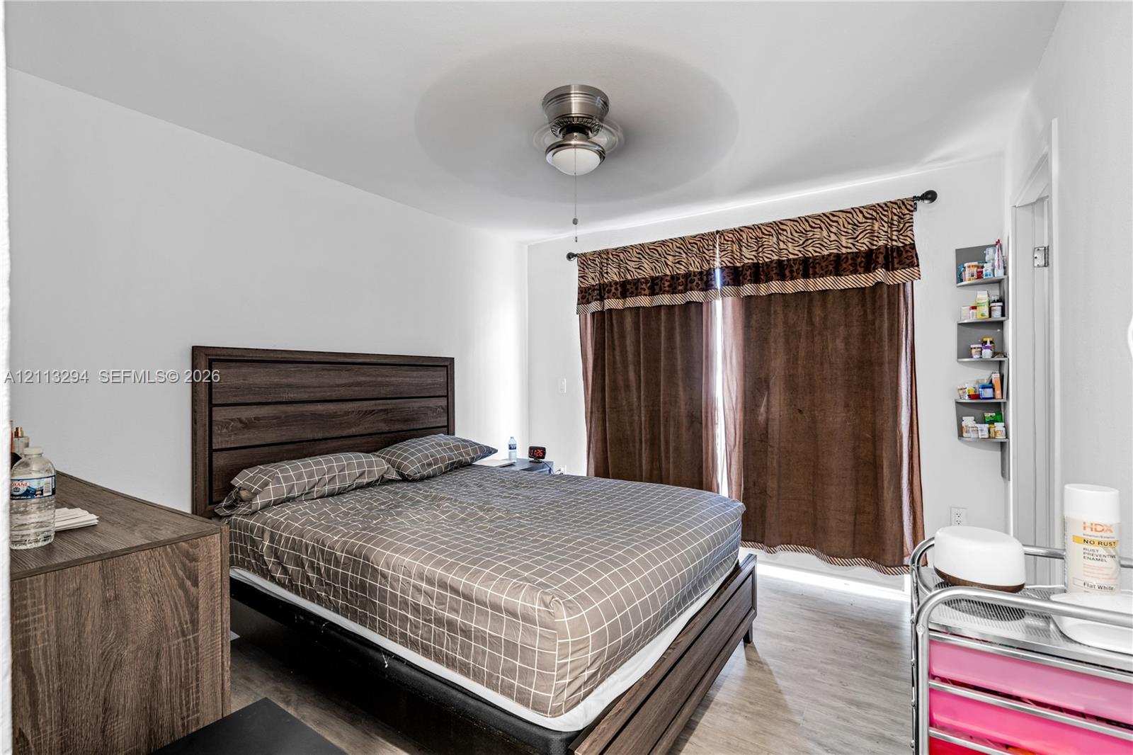 Wood-finish flooring, brushed nickel ceiling fan with integrated lighting, and wall-mounted shelving