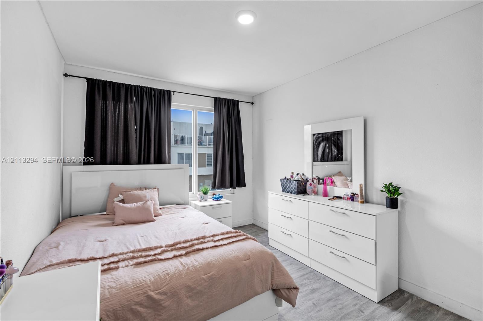 Neutral-toned interior featuring wood-finish flooring, recessed lighting, and a single-pane window with a black curtain rod