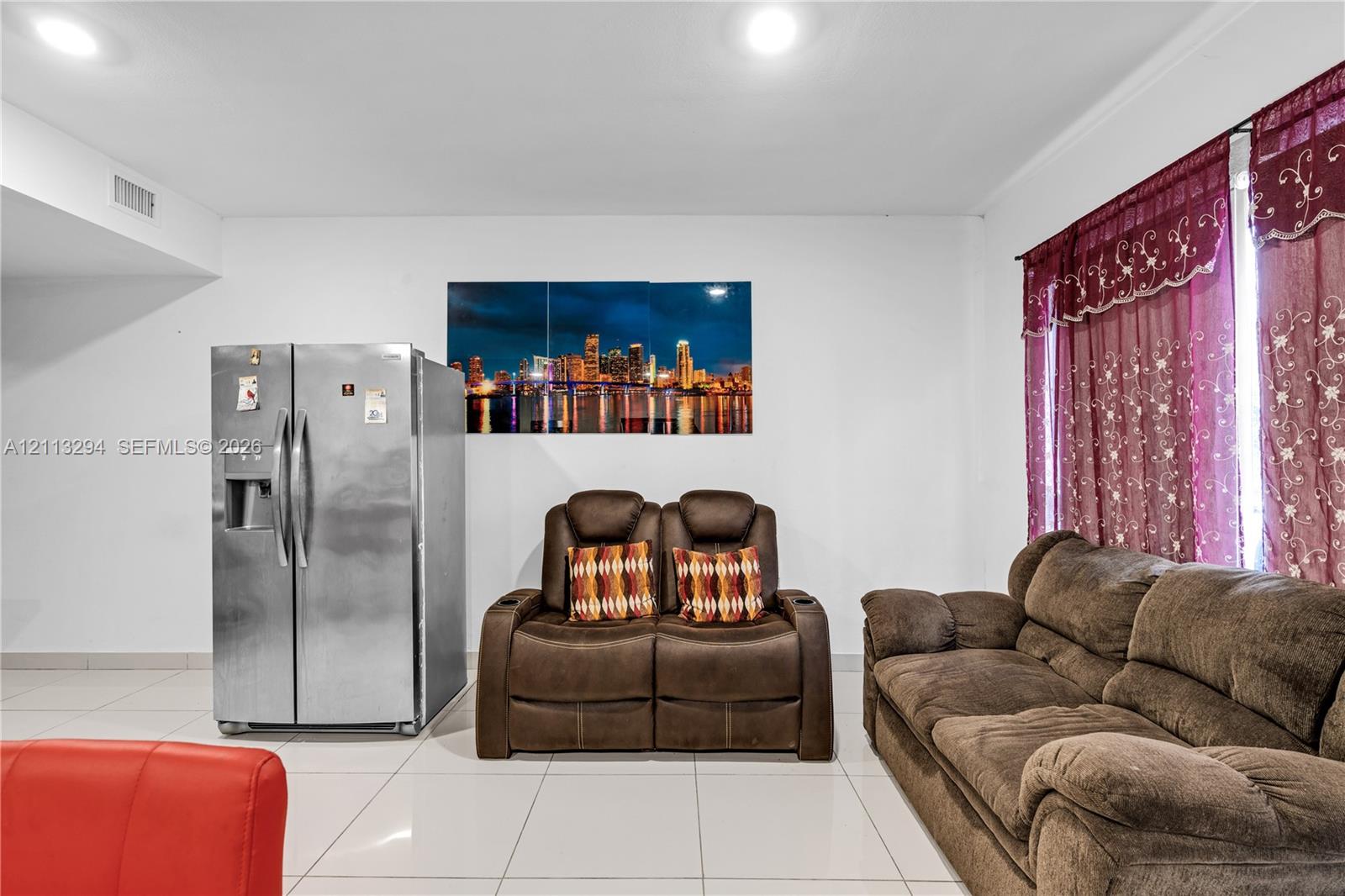 Interior space featuring large-format white tile flooring, recessed ceiling lighting, and a stainless steel side-by-side refrigerator