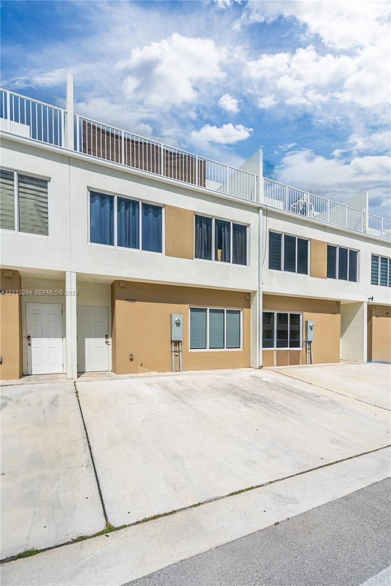 Contemporary multi-level exterior featuring white and tan stucco cladding, horizontal window groupings, a flat roofline, and a private rooftop terrace with metal railings Contemporary multi-level exterior featuring white and tan stucco cladding, horizontal window groupings, a flat roofline, and a private rooftop terrace with metal railings