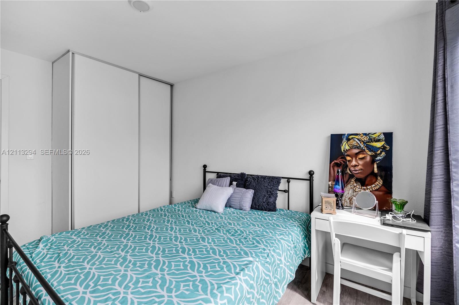Room featuring neutral wall paint, wood-finish flooring, and a floor-to-ceiling built-in wardrobe with sliding doors