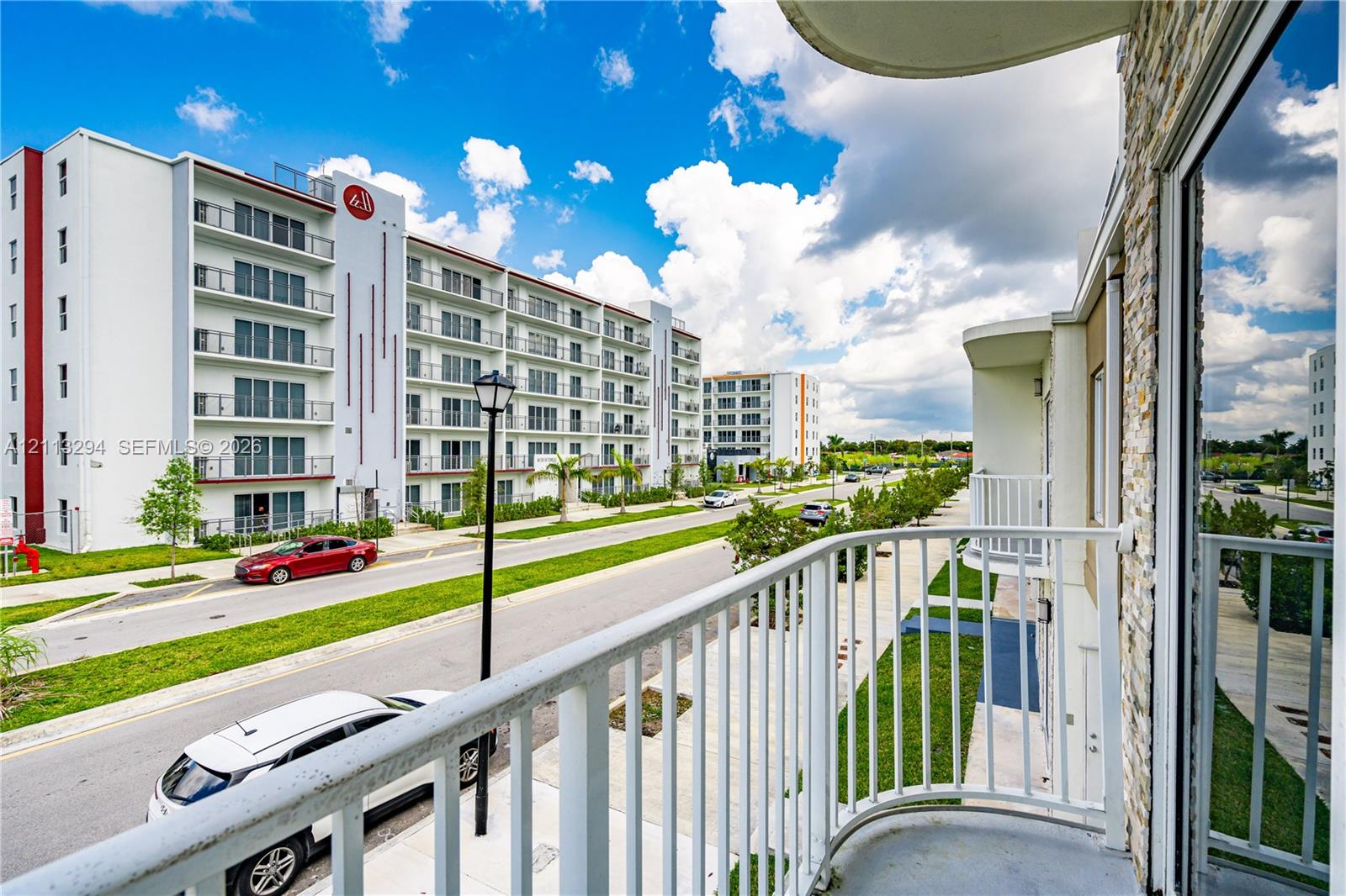 Private balcony featuring curved white metal railing and stone-veneer exterior wall