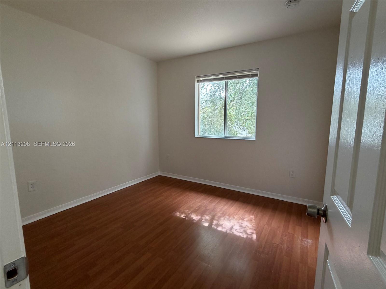 Neutral-toned interior space featuring wood-finish flooring and a single-pane window