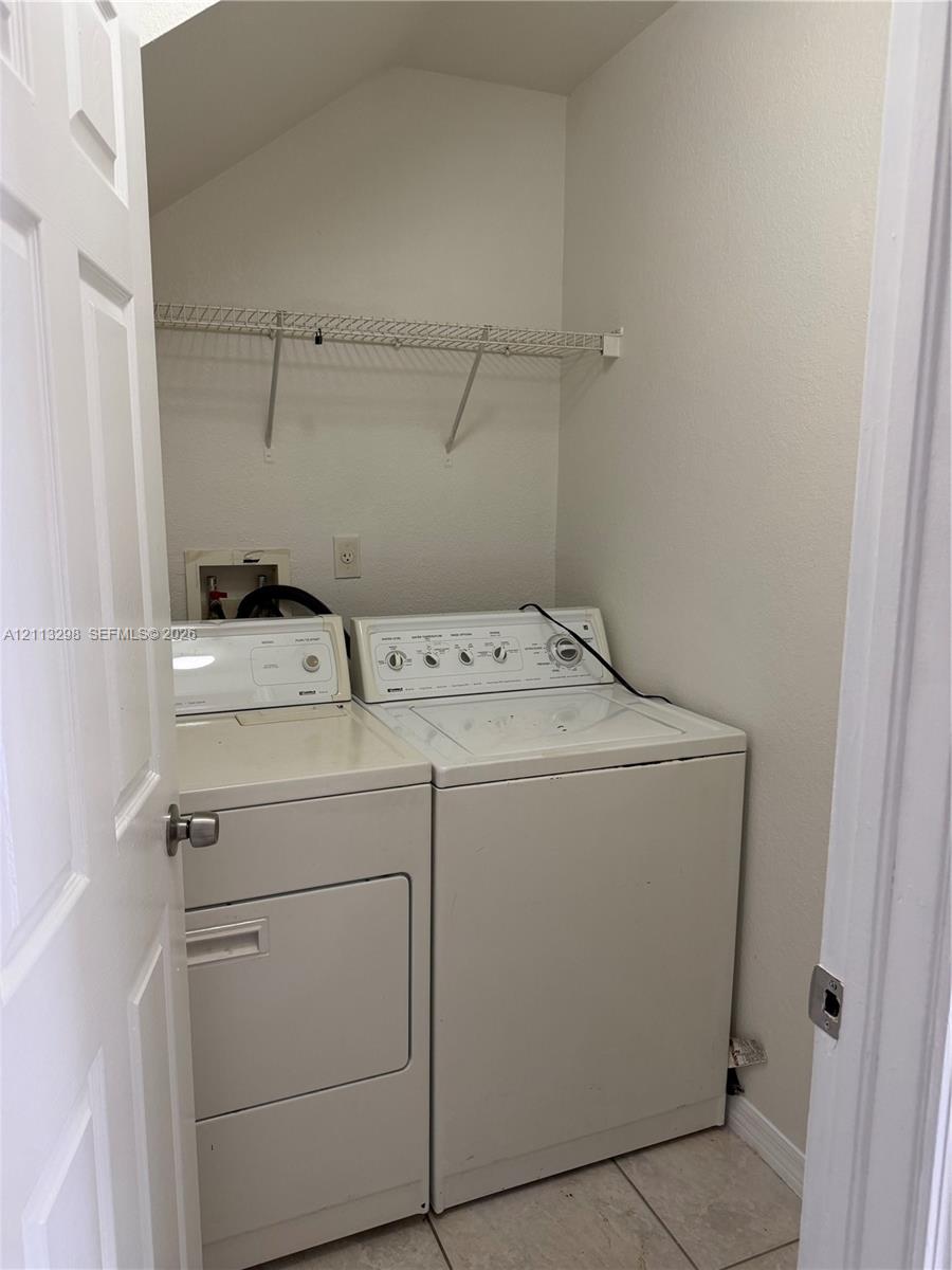 Dedicated laundry area featuring tile flooring and integrated wire shelving