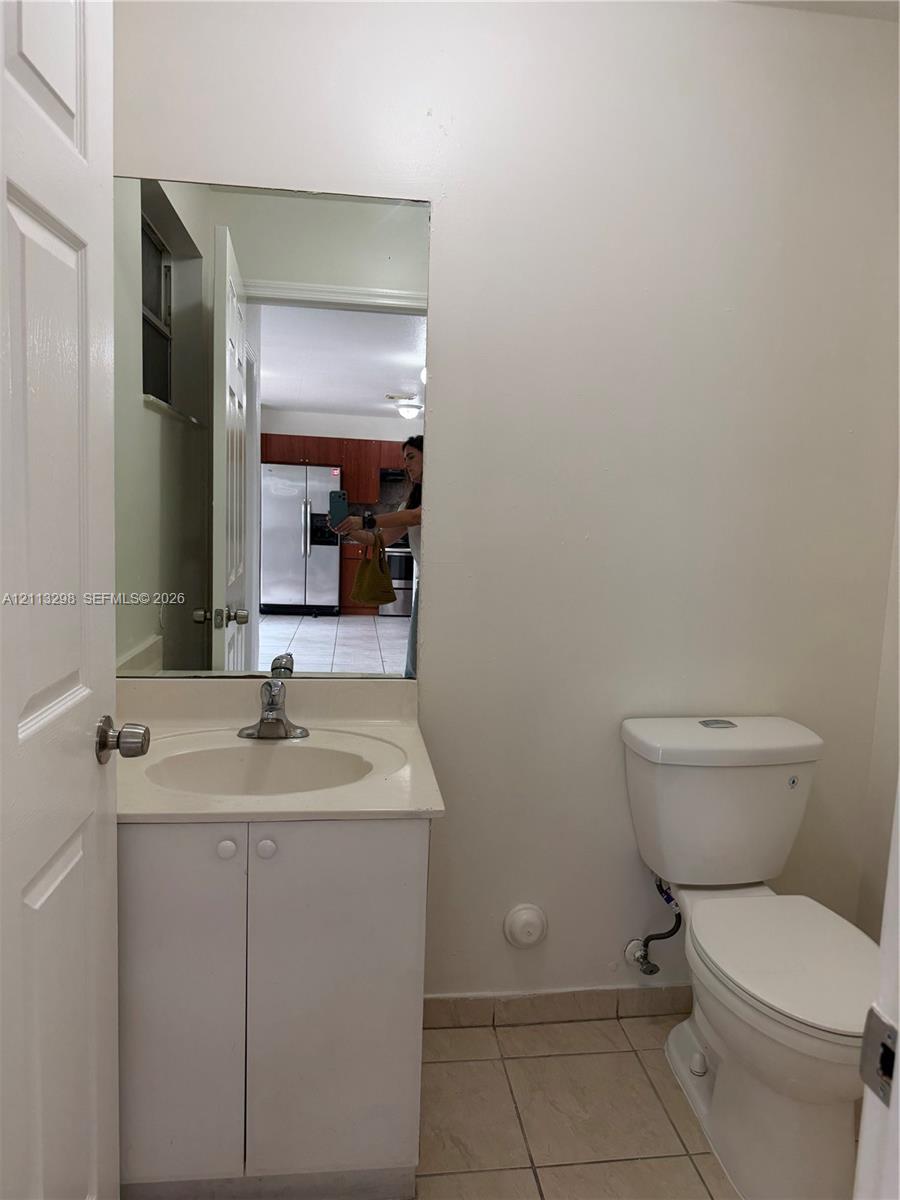 Wall-mounted vanity featuring a solid-surface integrated countertop, porcelain basin, single-handle faucet, and ceramic tile flooring