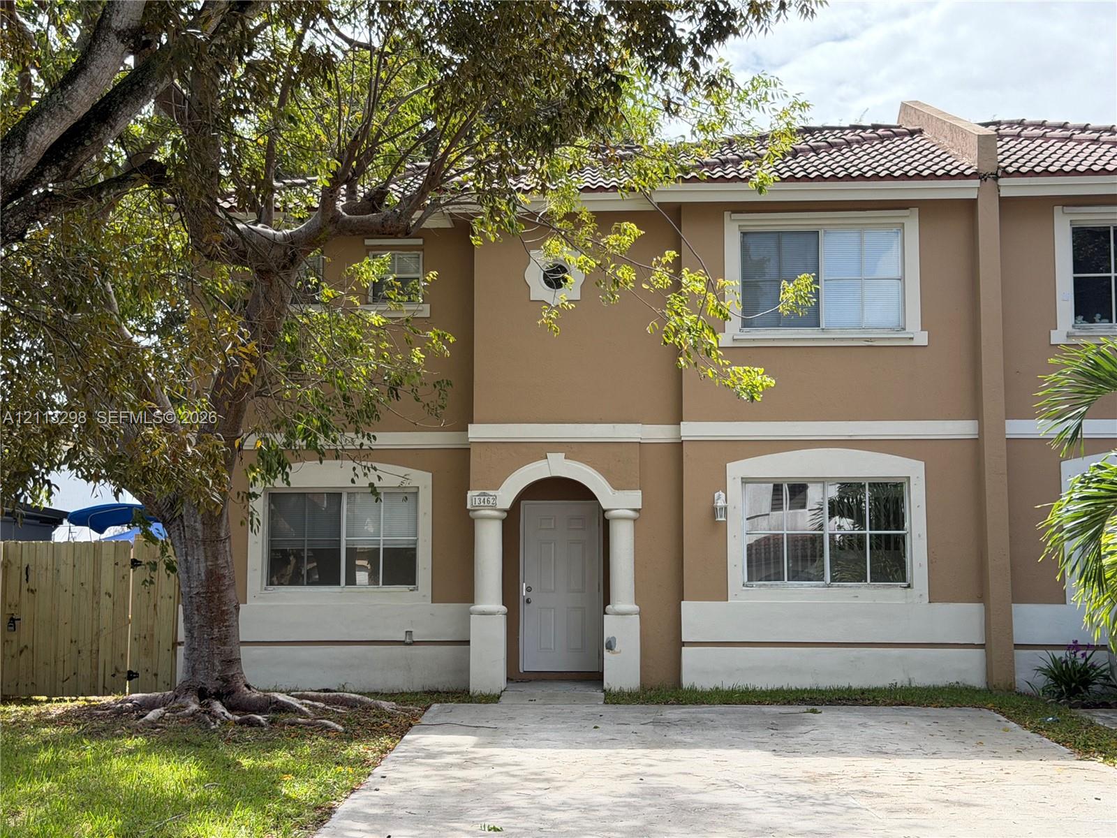 Two-story exterior featuring a stucco facade, concrete tile roof, arched entryway with decorative columns, and a concrete driveway Two-story exterior featuring a stucco facade, concrete tile roof, arched entryway with decorative columns, and a concrete driveway