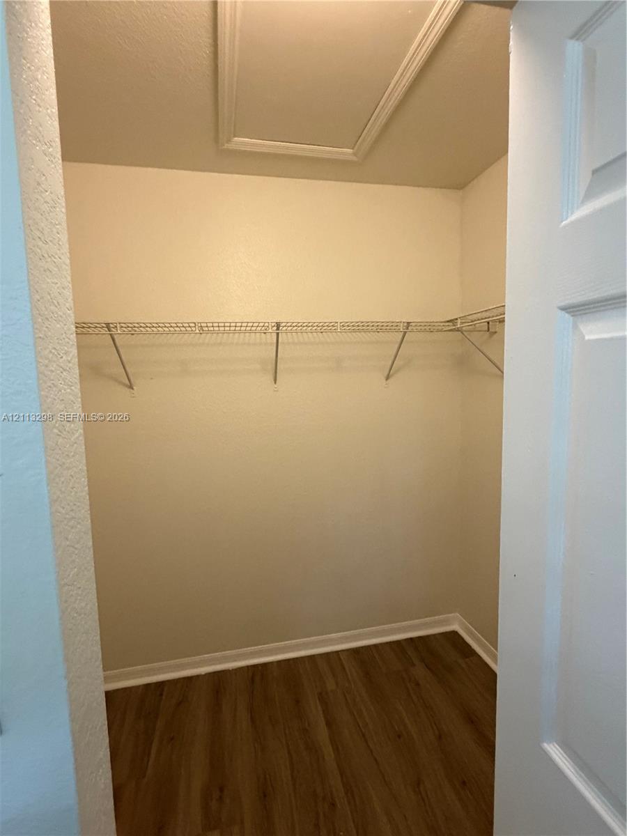 Storage area featuring wood-finish flooring, white walls, and wire shelving