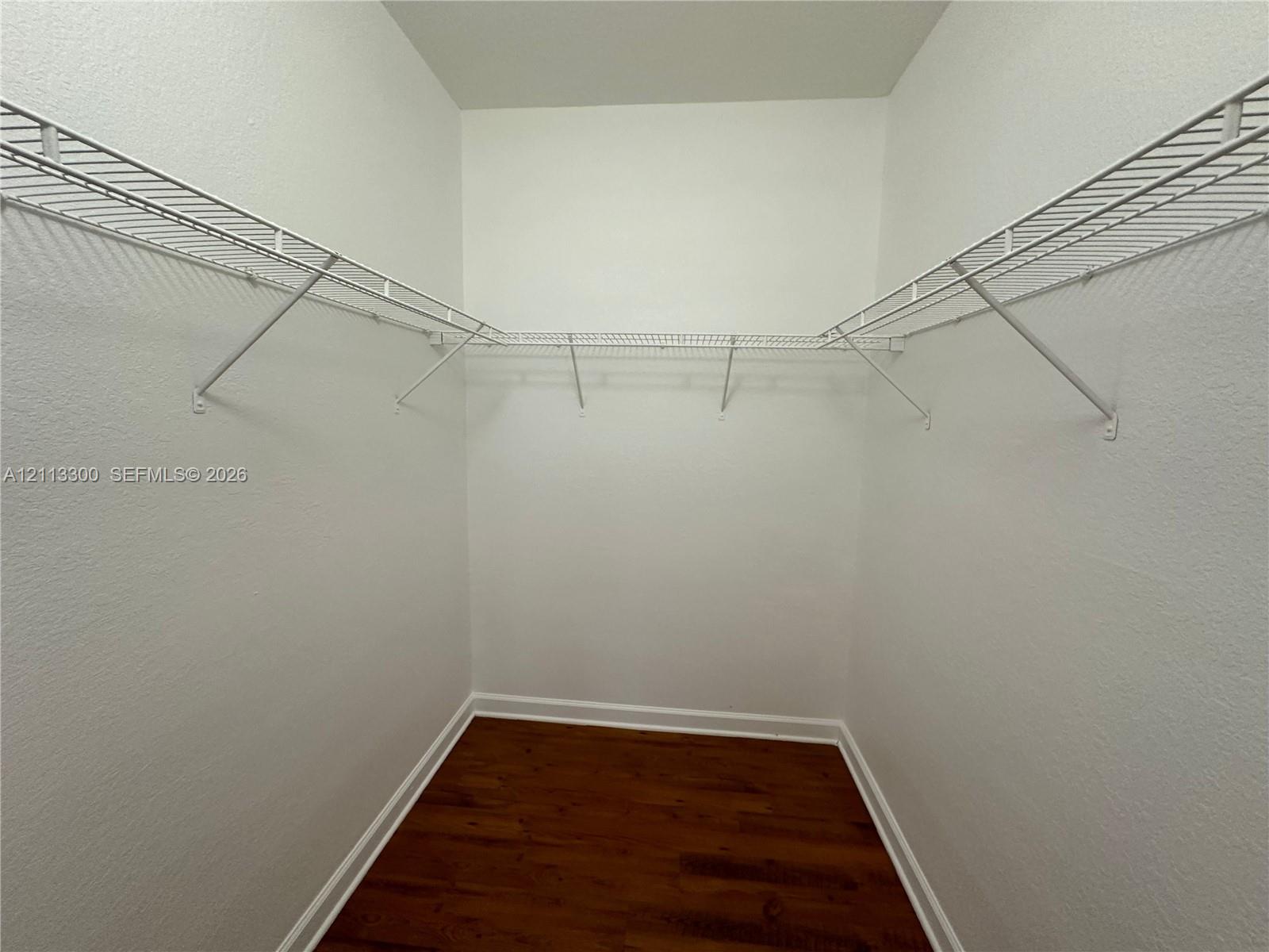 Walk-in storage space featuring wood-finish flooring and installed white wire shelving