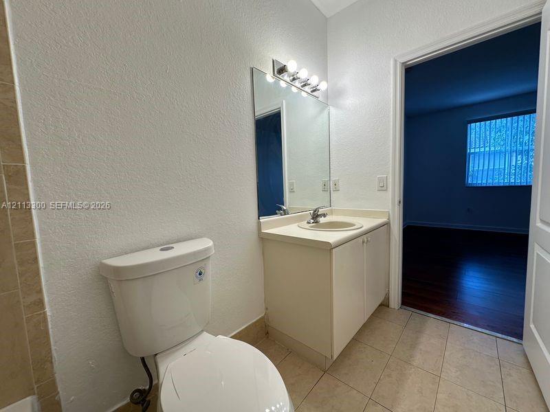 Bathroom featuring a vanity with an integrated countertop sink, a full-width vanity mirror, a multi-bulb light fixture, and ceramic tile flooring