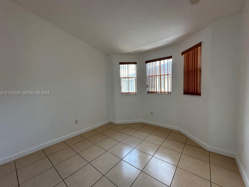 Room featuring tile flooring, a bay window configuration, and vertical window blinds